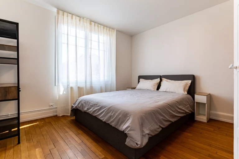 Chambre avec parquet en bois et fenêtres avec rideau