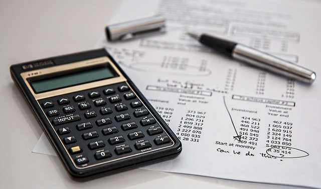 calculatrice avec feuille et chiffres ainsi qu'un stylo ouvert le bouchon à côté