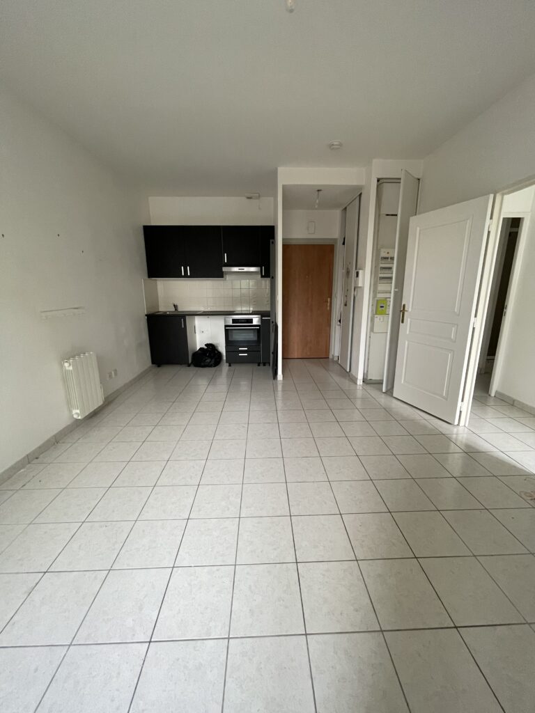 Pièce de vie dans un appartement T2 vide avec cuisine équipée